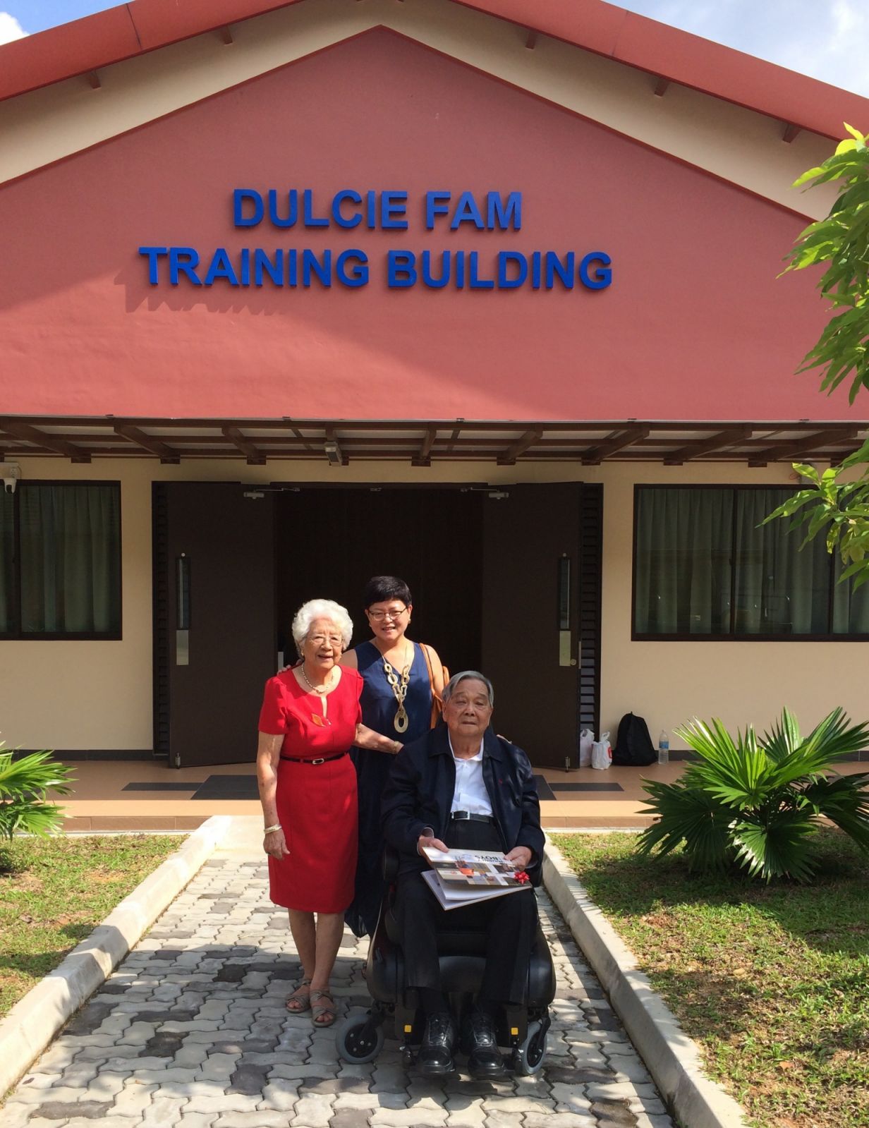 Anita Fam (centre) with mother Dulce Fam and father Dr Michael Fam in front of the Dulcie Fam Traning Building in Boys’ Town Singapore. (Photo: Anita Fam)