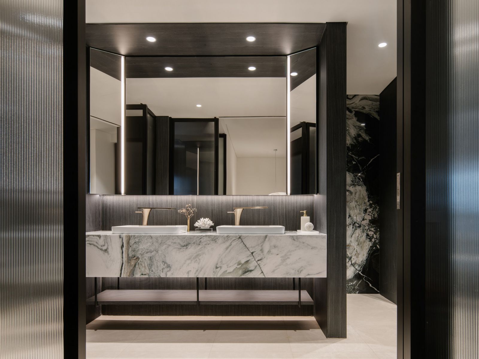 The bathroom contrasts darker structural elements with striking light-toned marble counters