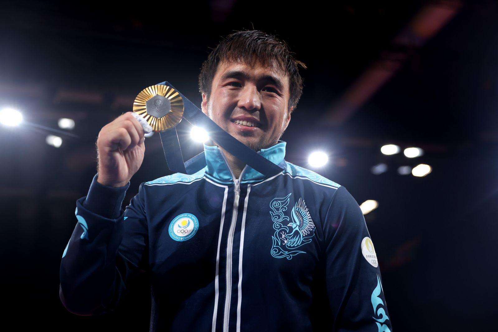 PARIS, FRANCE - JULY 27: Gold medalist Yeldos Smetov of Team Kazakhstan celebrates on the podium during the Men -60 kg Final ceremony on day one of the Olympic Games Paris 2024 at Champs-de-Mars Arena on July 27, 2024 in Paris, France. (Photo by Buda Mendes/Getty Images)